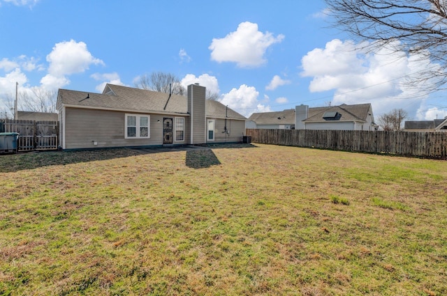 back of house with a lawn, a chimney, and a fenced backyard