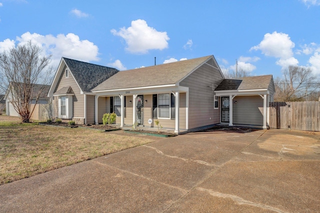 ranch-style home with driveway, a front lawn, fence, covered porch, and a shingled roof