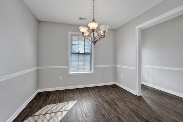 spare room with visible vents, baseboards, a textured ceiling, and dark wood-style flooring