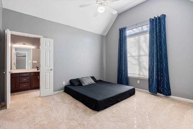 bedroom with baseboards, light carpet, lofted ceiling, and ensuite bath