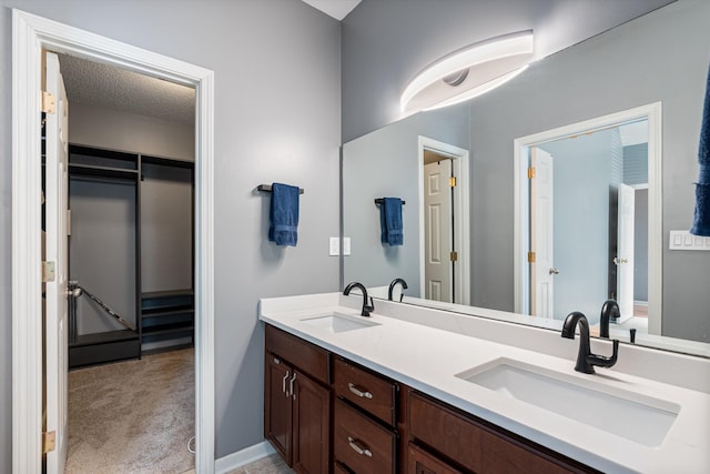 bathroom with a sink, a textured ceiling, and double vanity