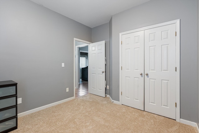 unfurnished bedroom with baseboards, light carpet, and a closet