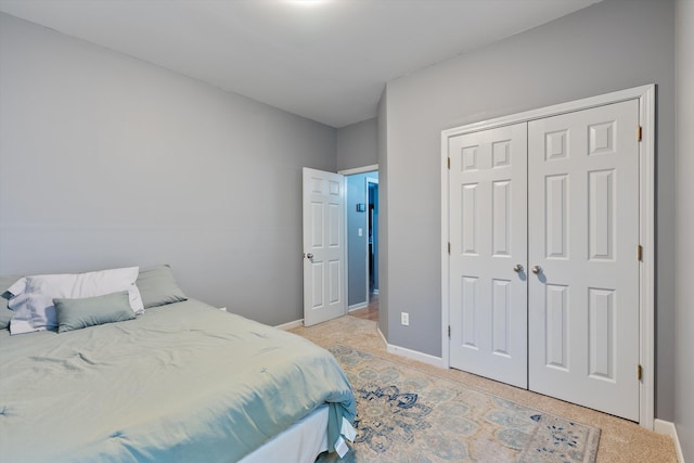 bedroom with baseboards, light carpet, and a closet