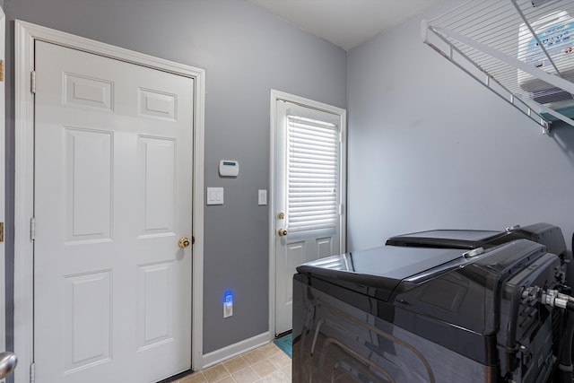 clothes washing area with laundry area, washing machine and dryer, and baseboards