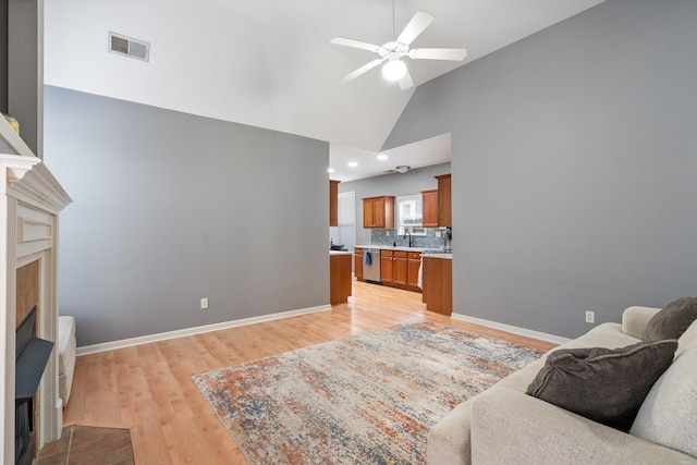 living room featuring visible vents, baseboards, light wood-type flooring, and ceiling fan