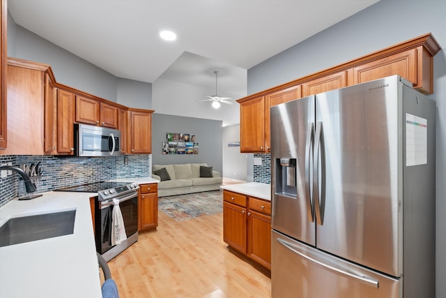 kitchen featuring tasteful backsplash, light countertops, light wood-style flooring, appliances with stainless steel finishes, and a sink