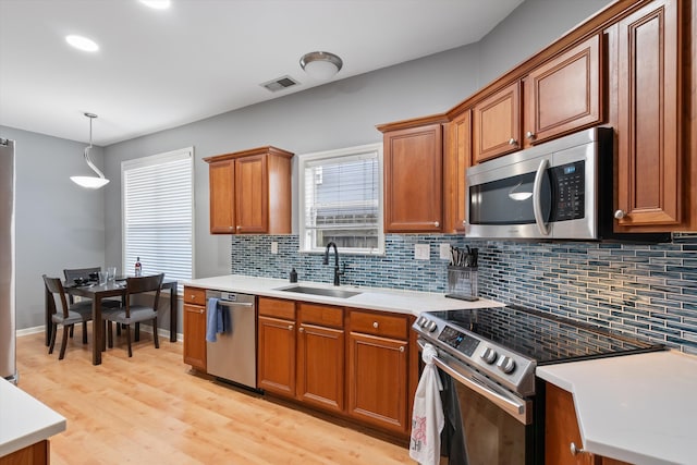 kitchen featuring visible vents, a sink, stainless steel appliances, light countertops, and backsplash