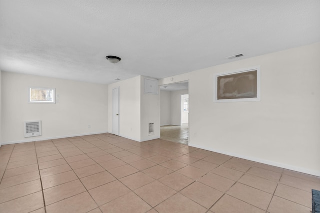 unfurnished room featuring light tile patterned floors, baseboards, and a textured ceiling