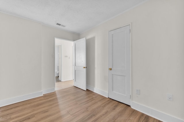 unfurnished bedroom with light wood finished floors, visible vents, a textured ceiling, and baseboards