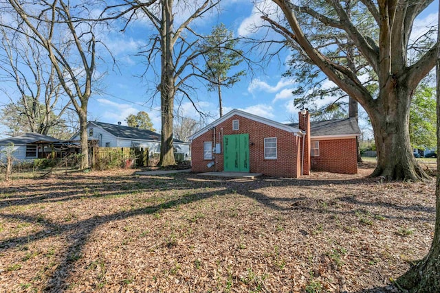 exterior space with brick siding, a chimney, and fence