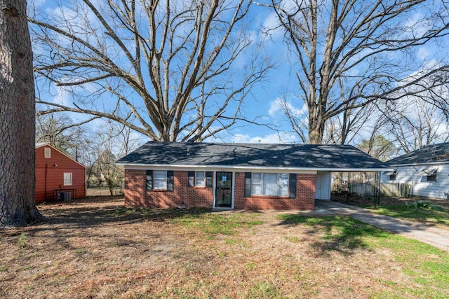 view of front of house featuring brick siding, an attached carport, driveway, and a front yard