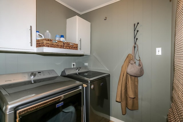 laundry room featuring ornamental molding, cabinet space, and washing machine and clothes dryer