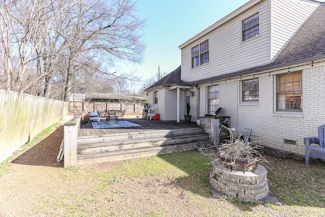 back of house featuring a wooden deck, a fenced backyard, a fire pit, crawl space, and brick siding