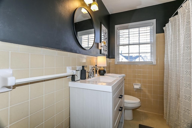 full bathroom with curtained shower, toilet, vanity, wainscoting, and tile walls