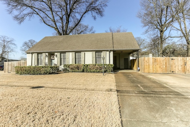 view of front of home with brick siding, concrete driveway, roof with shingles, and fence