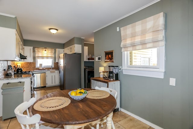 kitchen with ornamental molding, under cabinet range hood, tasteful backsplash, appliances with stainless steel finishes, and light tile patterned floors