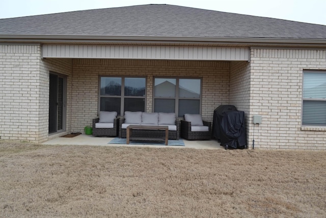 rear view of house with a patio, brick siding, roof with shingles, and outdoor lounge area