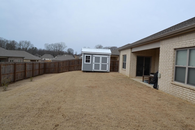 view of yard with an outbuilding, a fenced backyard, and a shed