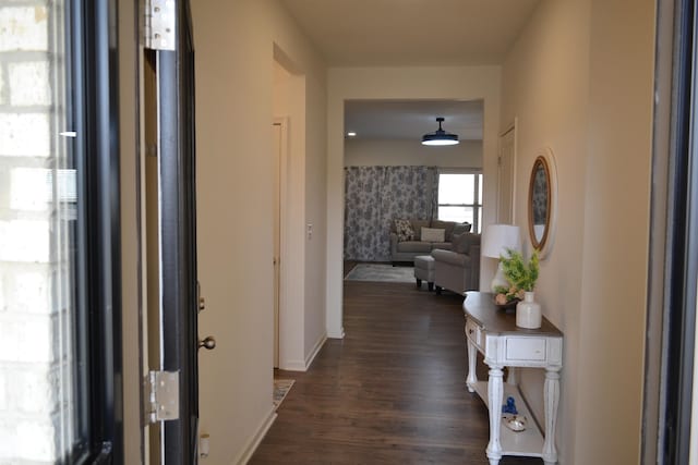 hallway featuring baseboards and dark wood-type flooring