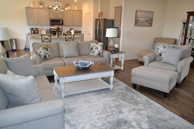 living room featuring a chandelier, dark wood-type flooring, and baseboards