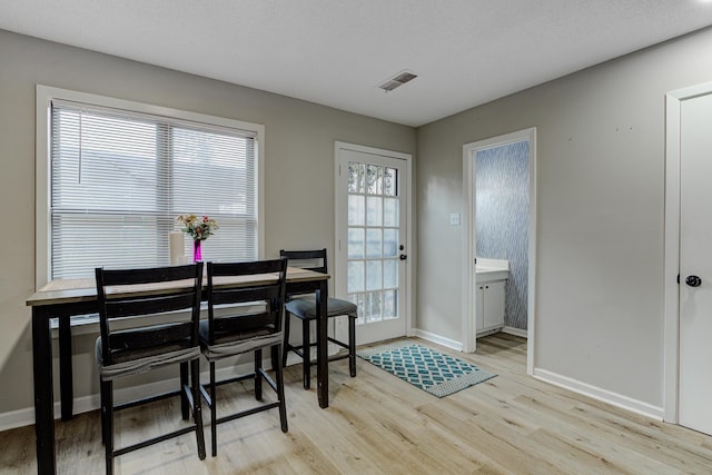 dining area featuring visible vents, baseboards, a textured ceiling, and wood finished floors