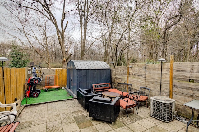 view of patio / terrace with a fenced backyard, central air condition unit, a storage unit, and an outdoor structure