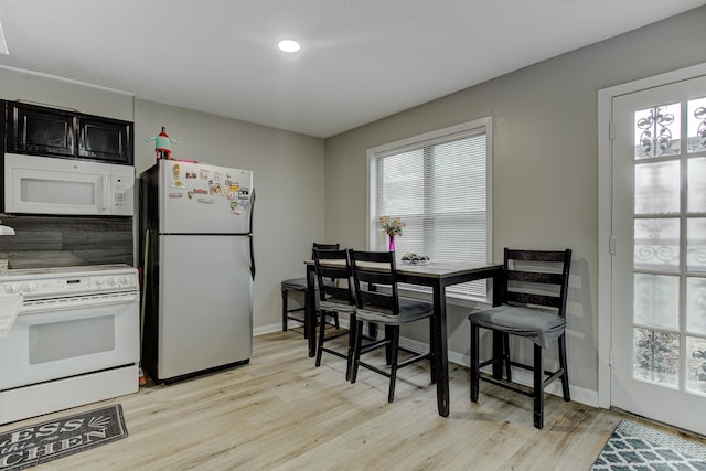 kitchen with a wealth of natural light, white appliances, and light wood-style floors