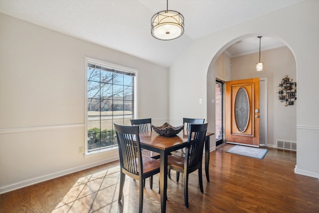 dining area with visible vents, lofted ceiling, wood finished floors, arched walkways, and baseboards