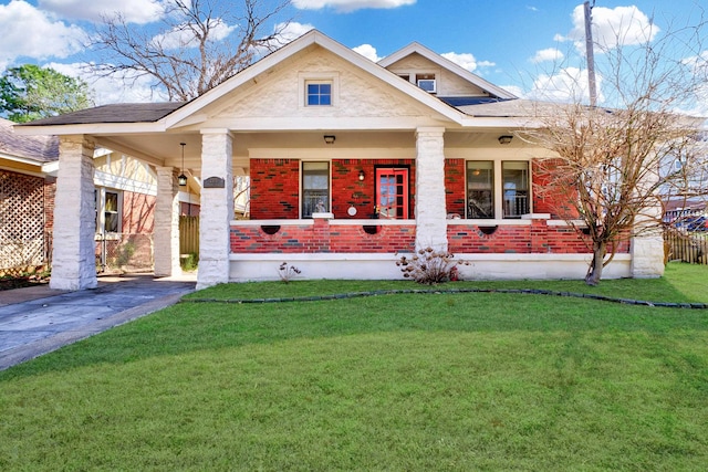 view of front of property featuring a front lawn, covered porch, brick siding, and roof with shingles