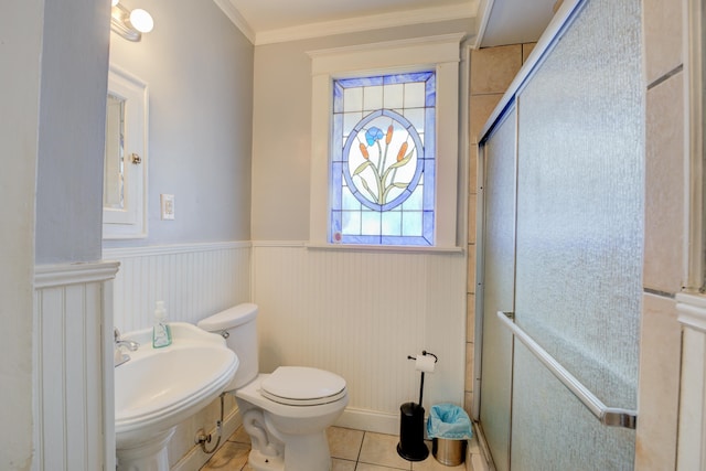 bathroom with a wainscoted wall, a sink, tile patterned flooring, crown molding, and toilet