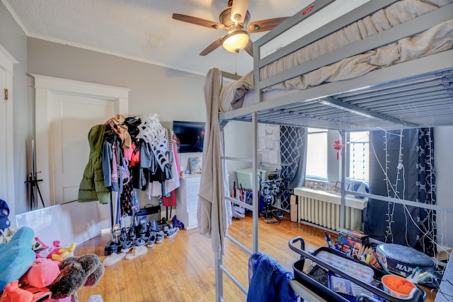 bedroom with ceiling fan, crown molding, wood finished floors, and a textured ceiling