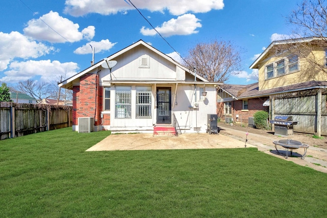 rear view of property featuring central AC unit, a yard, a fenced backyard, a patio area, and brick siding