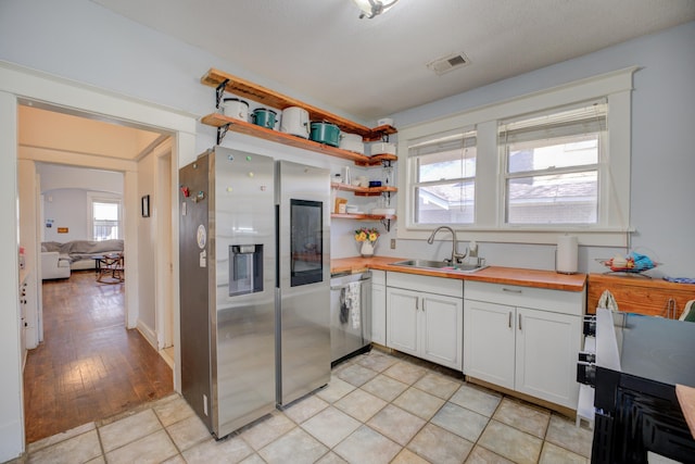 kitchen with visible vents, wooden counters, open shelves, a sink, and stainless steel appliances