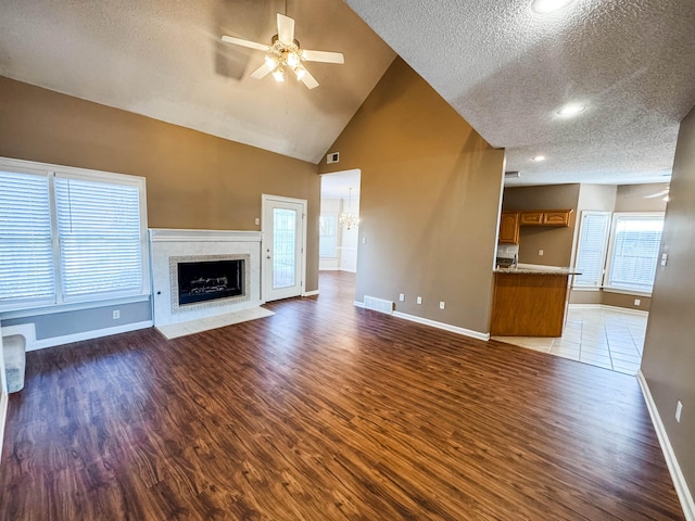 unfurnished living room with visible vents, a fireplace with flush hearth, a ceiling fan, and wood finished floors