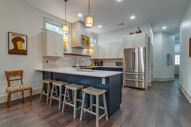 kitchen featuring light countertops, a peninsula, a kitchen breakfast bar, stainless steel appliances, and a sink