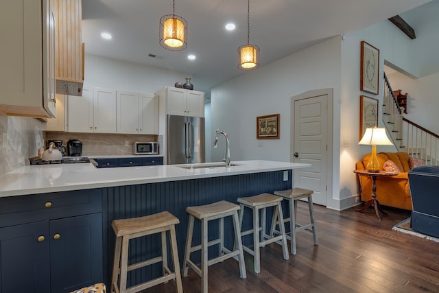 kitchen featuring a sink, appliances with stainless steel finishes, dark wood finished floors, and light countertops