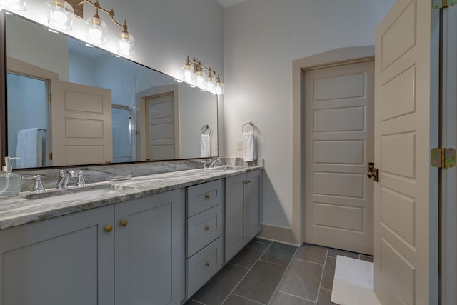 bathroom featuring a sink, a shower with shower door, double vanity, and tile patterned floors