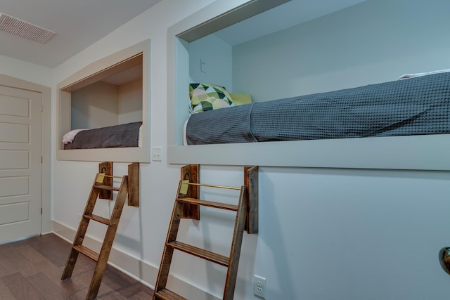 bedroom with wood finished floors, visible vents, and baseboards