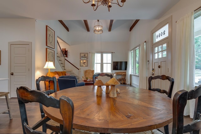 dining area with an inviting chandelier, beam ceiling, stairway, and wood finished floors