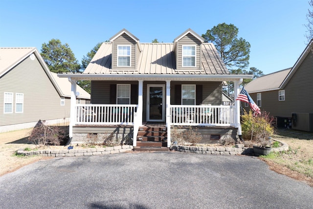 cape cod house featuring a porch and metal roof