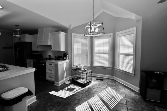 kitchen with lofted ceiling, decorative backsplash, black appliances, light countertops, and white cabinetry