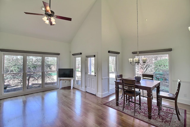 dining room with ceiling fan with notable chandelier, wood finished floors, baseboards, and high vaulted ceiling