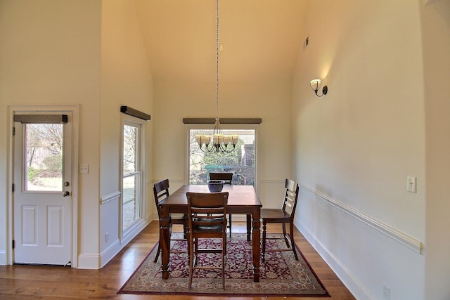 dining area with a chandelier, plenty of natural light, a high ceiling, and dark wood-style flooring