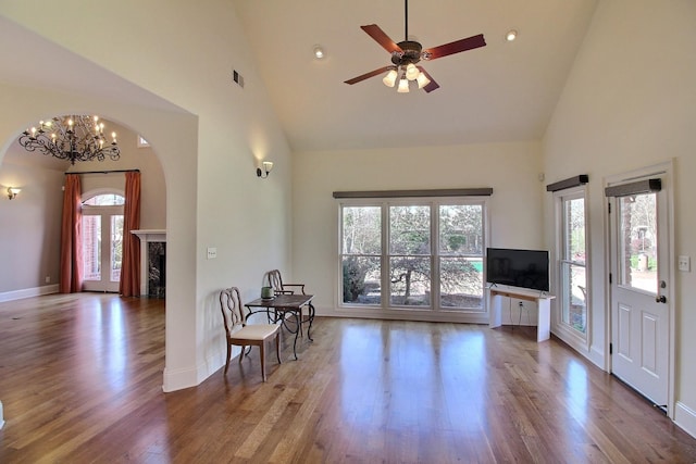 living area with baseboards, high vaulted ceiling, wood finished floors, and a fireplace