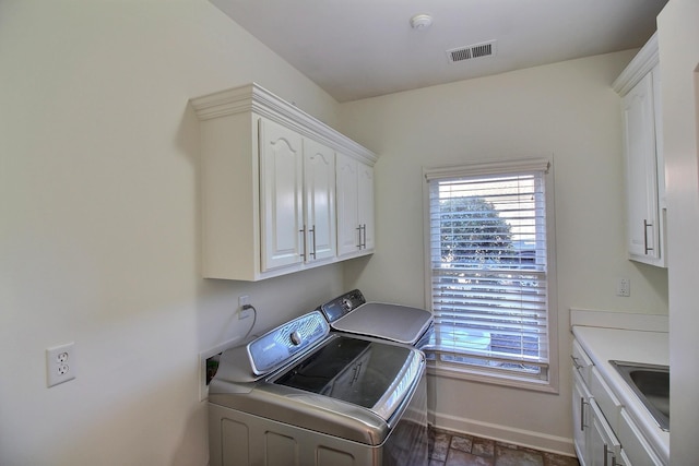 laundry room with visible vents, baseboards, cabinet space, separate washer and dryer, and a sink