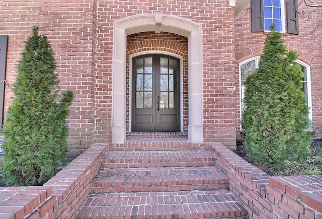 property entrance featuring french doors and brick siding