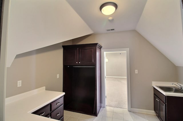 kitchen with visible vents, dark brown cabinets, light countertops, lofted ceiling, and a sink