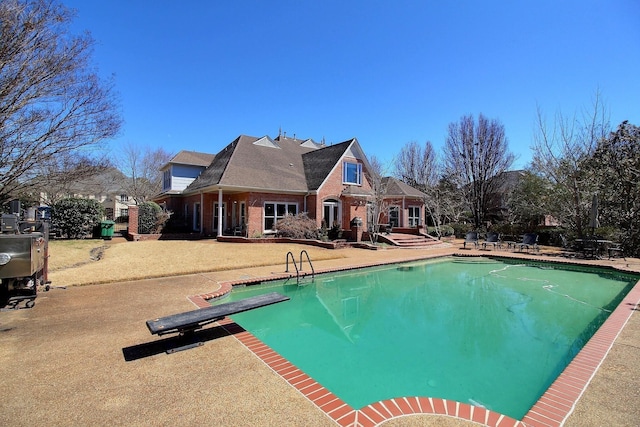 pool featuring a diving board and a patio