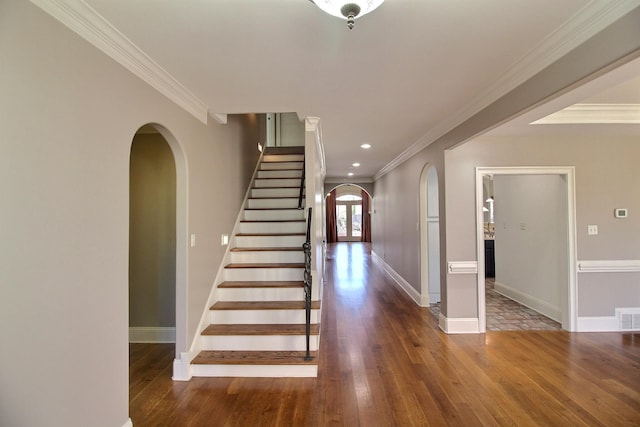 interior space with arched walkways, stairway, wood-type flooring, and ornamental molding