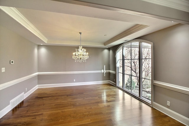 unfurnished dining area with visible vents, a tray ceiling, and wood finished floors